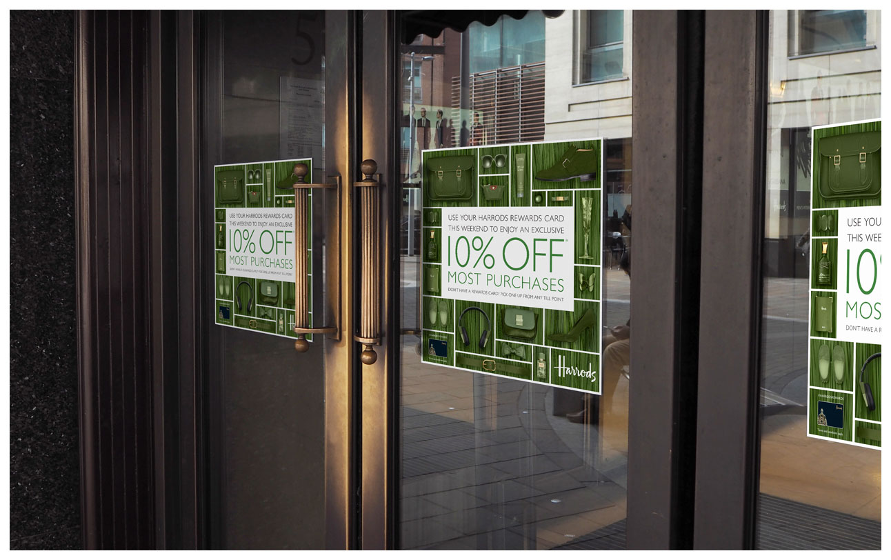 Door signs outside Harrods advertising the 10% weekend sale with green products on matching typha grass